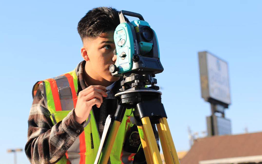 Young construction professional using a surveying instrument in the field